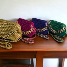 four different colored purses sitting on top of a wooden table next to each other