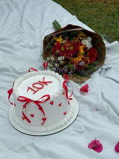 a white cake sitting on top of a table covered in flowers