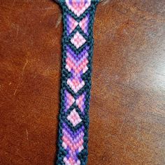 a close up of a wrist watch on a wooden table with a crochet pattern