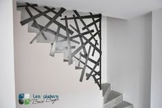 an artistic staircase made out of sticks and metal strips in a room with white walls