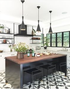 a kitchen with black and white tile flooring and pendant lights hanging from the ceiling