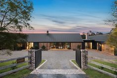 a large house with a driveway leading to the front door and two gates that lead into it