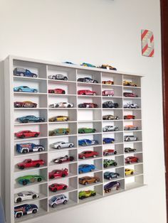 a white shelf filled with lots of toy cars on top of it's sides