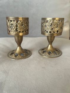 two golden candlesticks sitting on top of a white blanket