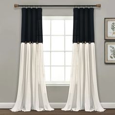 black and white curtains hanging in front of a window with two pictures on the wall