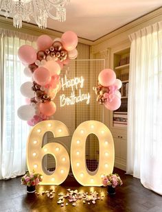 a birthday party with balloons and lights in the shape of the number sixty, surrounded by confetti