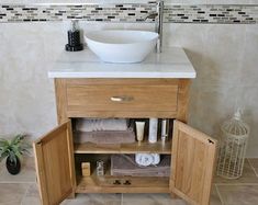 a bathroom with a sink and wooden cabinet in the corner next to a tiled wall