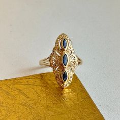 Estate/ vintage 14KT yellow gold blue sapphires and diamond filigree, Art Deco design ring. Faceted, navy blue, marquise sapphire elongate along the ring with intricate gold detailing and diamonds. Size 6.25 Sizable by your local jeweler or us for a fee Weight: 3.30 grams Stamped & Hallmarked Fully tested, including the stones Diamond Art Deco Ring, Marquise Sapphire, Saint Jewelry, Art Deco Diamond Rings, Blue Sapphire Diamond, Deco Ring, Art Deco Ring, Art Deco Design, Sapphire Diamond