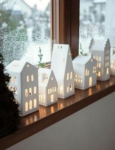 small white houses are sitting on a window sill in front of the windowsill