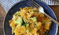 a blue plate topped with broccoli and cheese casserole next to a fork