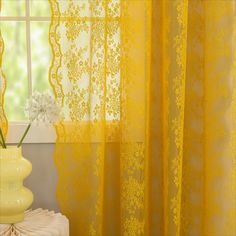 a vase with flowers in it next to a yellow curtain and some windowsills