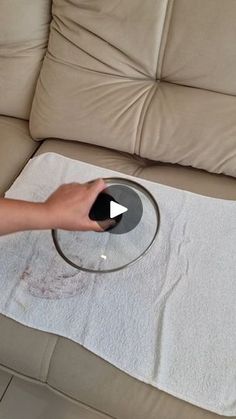 a person is cleaning a couch with a rag and a glass on the floor next to it