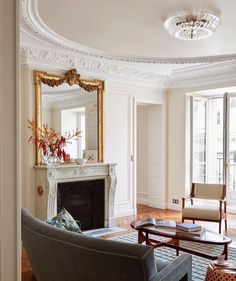 a living room filled with furniture and a fire place under a mirror on the wall