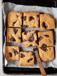 chocolate chip cookie bars cut into squares and placed on top of parchment paper with a spatula