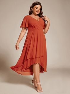 a woman in an orange dress posing for the camera with her hands on her hips