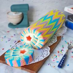 a colorful cake sitting on top of a cutting board next to a knife and fork