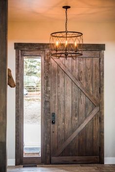 an open wooden door with a chandelier hanging from it's center beam