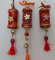 three red and gold bells hanging from the side of a wall with tassels