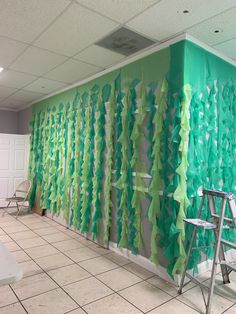 a room that has some green decorations on the wall and chairs in front of it