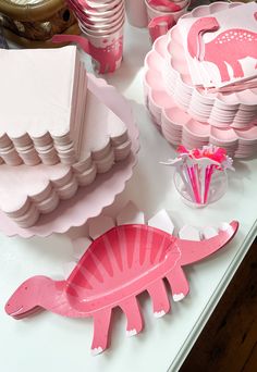 a table topped with plates and cups filled with pink paper animals on top of it