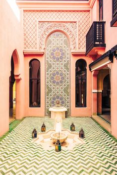 an ornate courtyard with a fountain and tiled floor in the center, surrounded by pink walls