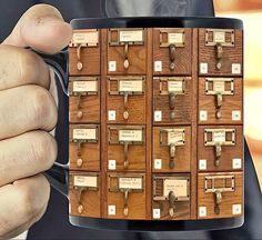 a man holding a coffee mug with lots of drawers on it