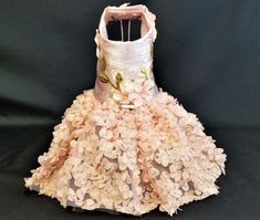 a dress made out of pink flowers on a black background with white and gold trim