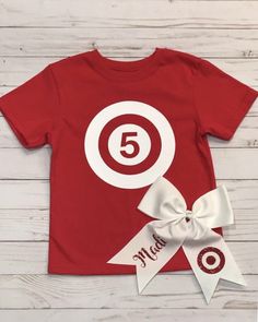 a red t - shirt with the number five on it and a white ribbon tied around it