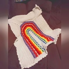 a crocheted blanket with a rainbow design on it sitting on top of a couch