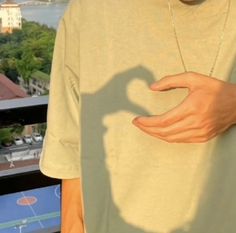 a man holding his hand out in front of him with a shadow on the shirt