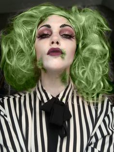 a woman with green hair and makeup is dressed in black and white striped shirt, bow tie