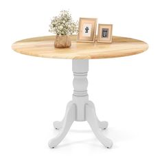 a wooden table with two pictures on it and a small vase filled with baby's breath flowers