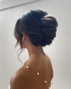 a woman in a white dress with pearls on her neck and hair styled into a low bun