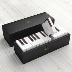 an open box with piano keys in it on a white wooden floored surface next to a pentawards logo