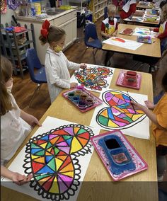 children are sitting at desks in a classroom with stained glass designs on the table