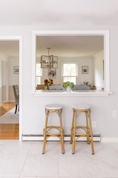 two stools sitting in front of a mirror on the wall next to each other