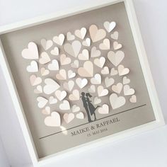 a white frame with paper cut hearts in the shape of a couple holding each other