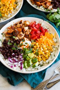 three bowls filled with different types of food on top of a blue cloth next to silverware