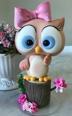 an owl figurine sitting on top of a tree stump with flowers in the background