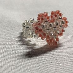 an orange and white beaded ring sitting on top of a white cloth covered table