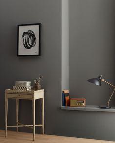 a desk with a lamp, books and pictures on the wall in front of it