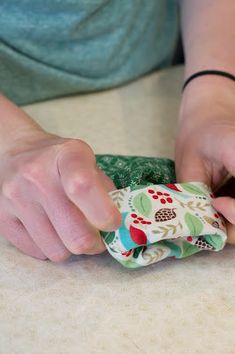 a person is wrapping something in a bag on the table with their hands and fingers