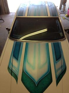 the hood of a white car with blue and green designs on it's side