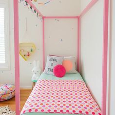 a child's bedroom with pink and green bedding, polka dot pillows and decorations