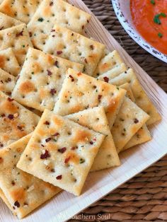 crackers on a plate next to a bowl of sauce