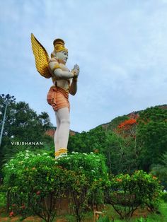 a statue of an angel holding a bird in its hands and standing on top of a bush