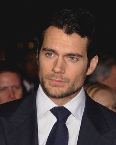 a close up of a person wearing a suit and tie with people in the background