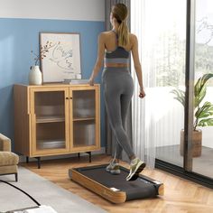 a woman standing on top of a scale in a living room next to a window