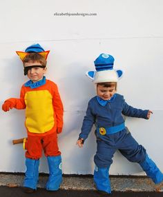 two young boys dressed up in costumes standing next to each other against a white wall