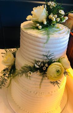 a wedding cake with white flowers and greenery